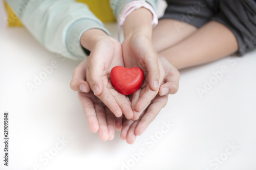 Tow child holding red heart, closeup. Adoption concept