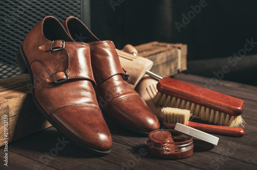 Leather shoes and shoe polish equipment on a wooden composition