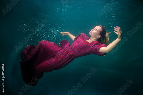 Woman in a red dress is underwater, she is sleeping.