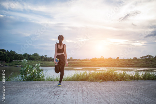 Healthy young woman warming up outdoors workout before training session at the park.