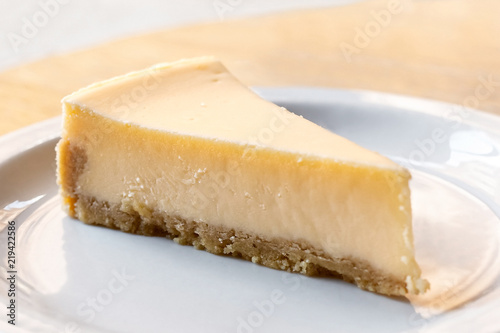 A slice of plain baked cheesecake on white plate.