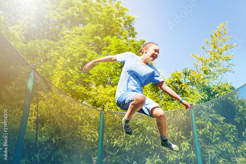 Excited girl jumping on the trampoline outdoors