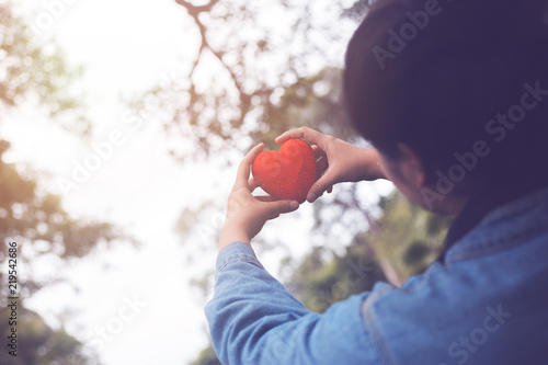 A woman looks at heart toy in his hand. Raised over head