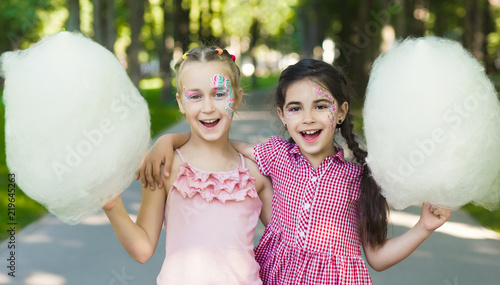 Happy female friends in amusement park with cotton candy