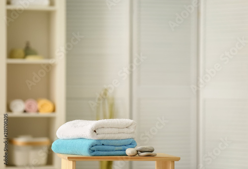 Clean towels and stones on table against blurred background