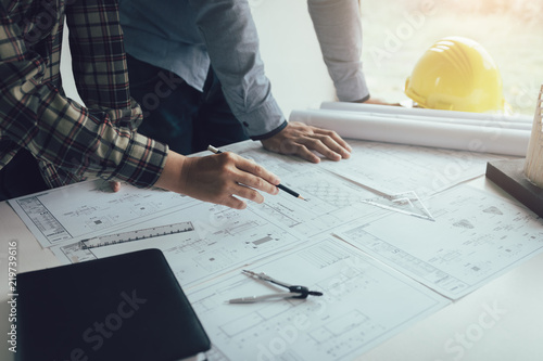 Two engineering man working with blueprints and discussing project together at the meeting in the office.