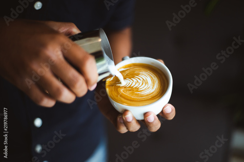 Barista making a cup of coffee latte art in coffee shop..