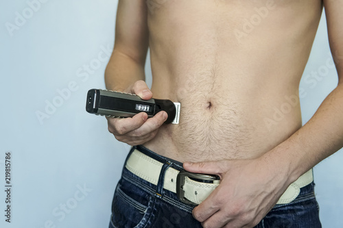 closeup of a young man trimming the hair of his pubis with an electric trimmer. concept of a clean healthy body for men. Man haircut pubic hair with a clipper.