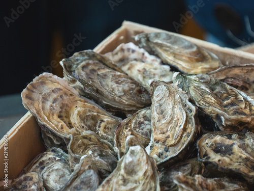 Oysters on the counter in wooden boxes on the market. Oysters for sale at the seafood market. Fish market stall full of fresh shell oysters. Fresh oysters selective focus. Close up shot.