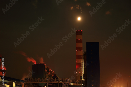 Elektrownia, fabryka w świetle księżyca w pełni nad kominem.