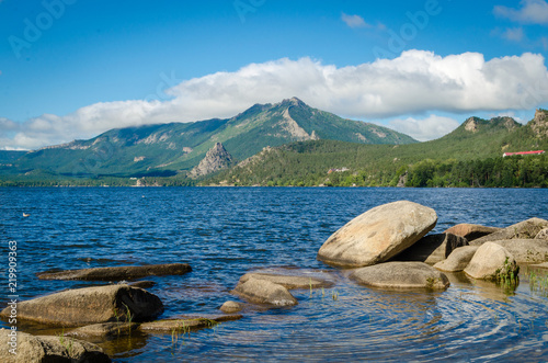 Large boulders in the blue lake against the mountains.