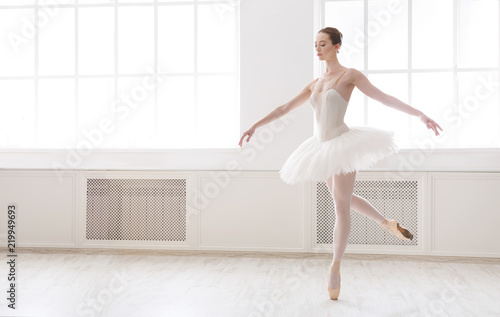 Beautiful ballerina in tutu skirt near large window
