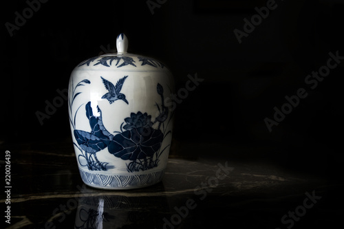 Antique Chinese porcelain jar in an auction against a black background. Empty copy space for Editor's text.