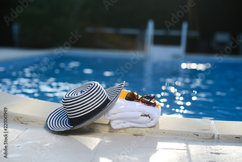 sun hat, towel, sunscreen by the poolside, swimming pool luxury summer holiday concept hotel club spa resort