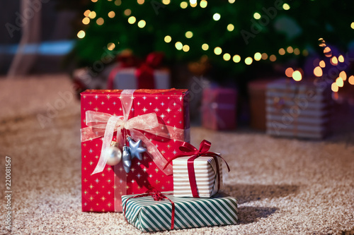 Beautiful Christmas gift boxes on floor near fir tree in room