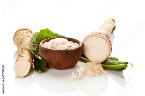 Fresh and grated horseradish in wooden bowl.