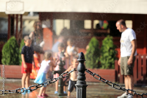Dzieci bawią się, pryskają wodą przed restauracją.