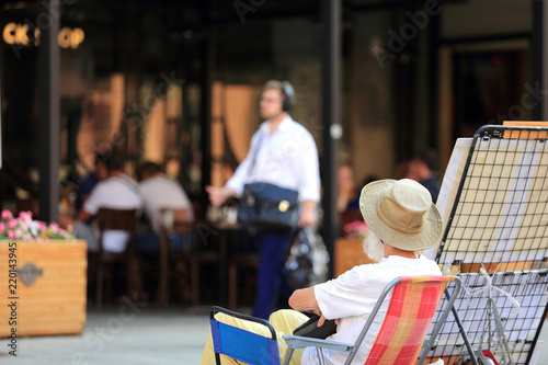 Stary mężczyzna siedzi na fotelu przed restauracją.