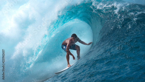 CLOSE UP: Crystal clear water splashes over surfer riding an epic barrel wave.