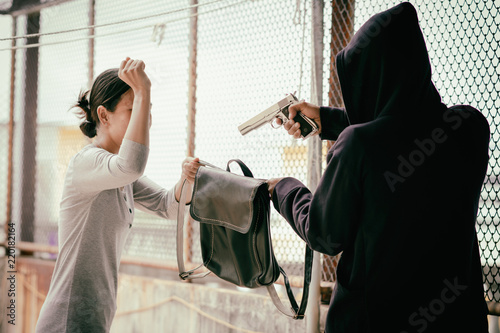 villain is using a gun to rob a bag from a woman.