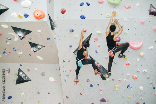 Couple enjoying climbing on artificial wall in gym
