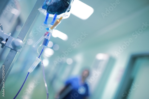 Intravenous drip with blue liquid ready to use on the background of walking around medical doctor, concept of mercy killing