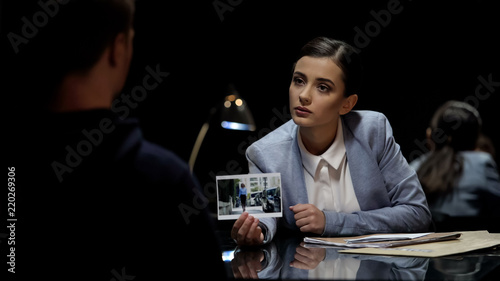 Investigation officer showing murder suspect victim photo, police interrogation