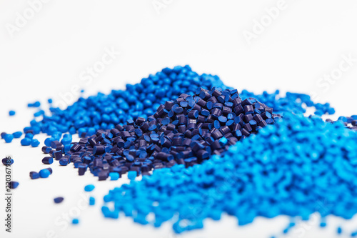 Stacks of a blue plastic polymer granules on a white background, copy space