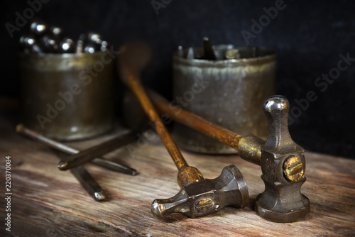 old vintage hammers and hallmark steel punches on a rustic wooden workbench of a goldsmith against a dark background