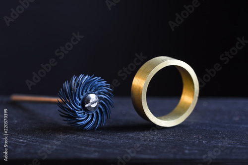 ring from gold and a polishing tool on the workbench of a goldsmith against a dark background with copy space