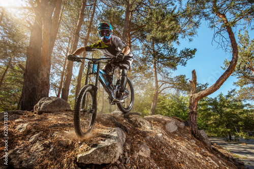 Mountain biker on forest trail. Male cyclist rides the rock