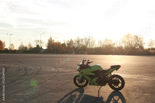 Green sport motorbike on the background of gray asphalt. Motorcycle on the parking lot. Sunset. Ukraine, Lviv