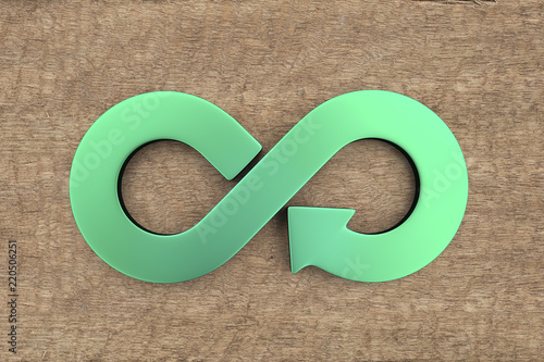 Circular economy concept. Green arrow infinity recycling symbol on wooden background.