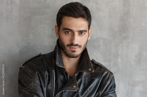 Close up portrait of serious, bearded macho man in cool leather jacket