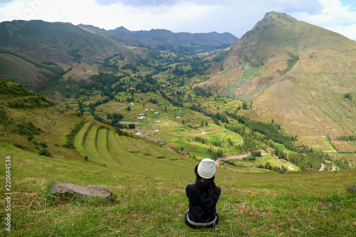 Female tourist sitting on the mountain slope of Pisac Archaeological Complex, Sacred Valley, Cusco region, Peru 