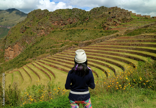 One female tourist admiring the Inca ancient agricultural terraces at Pisac Archaeological Complex, Sacred Valley, Cusco region, Peru 