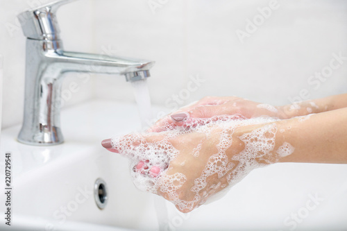 Washing hands with soap under the faucet with water.