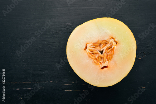 Fresh melon Sliced to pieces of melon. On a black wooden background. Free space for text. Top view.