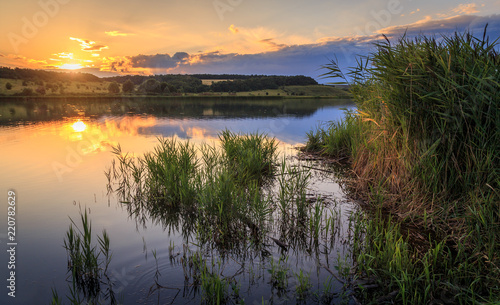 Sunset on the lake. The water reflects the setting sun and clouds.