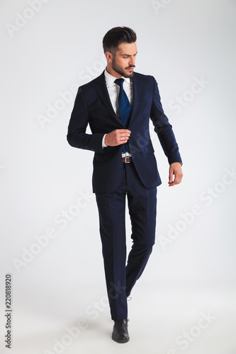 young businessman walking and buttoning his navy suit