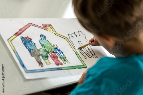 Child colouring in a sketch of a family using a paintbrush