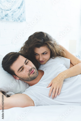 beautiful happy young woman hugging boyfriend sleeping on bed