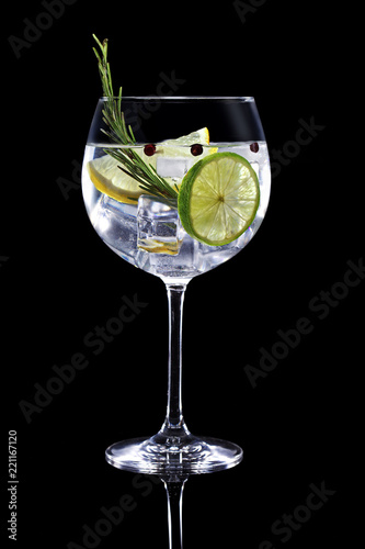 gin tonic garnished with citrus fruit and rosemary isolated on black background