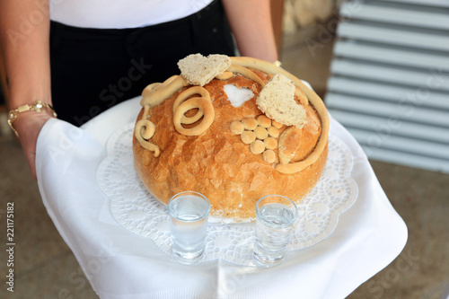 Kelnerka trzyma bochenek chleba z solą, wodą i wódką na przywitanie młodej pary.