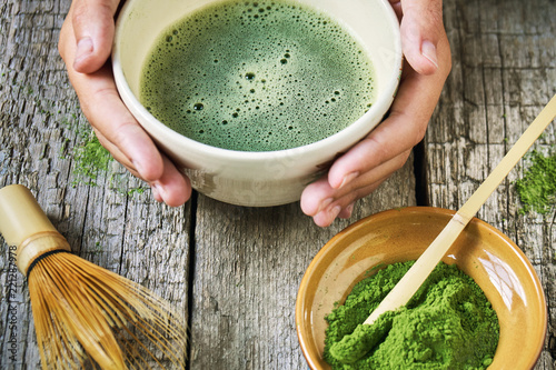 Girl's hands holding matcha tea in special matcha tea bowl with bamboo spoon and whisk