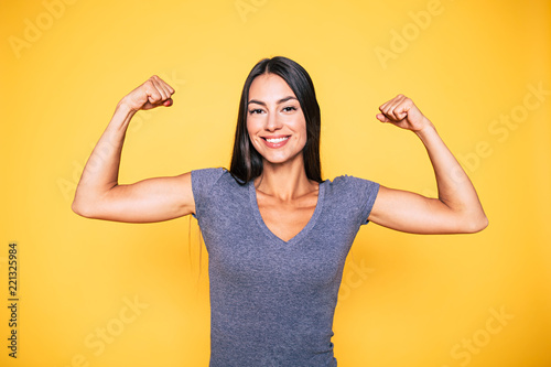 Sport, healthy lifestyle, gym, good body condition, women health, fitness concepts. Close up Portrait of Young cute sporty smiling brunette woman while she shows her arms and biceps on camera