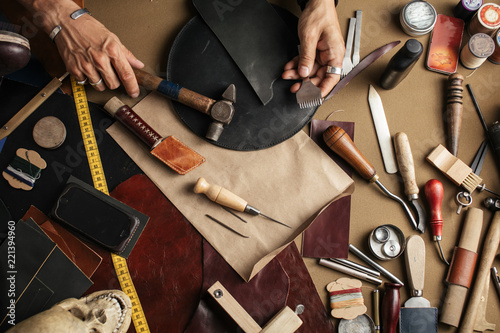 Top view of male shoemaker hands holding cobbler tools for making new shoes at his workshop over his working place background