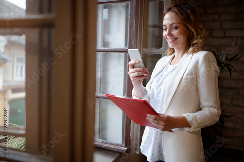 Business woman in office dialing with cell phone