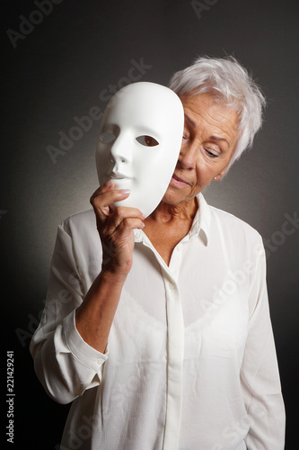 mature woman revaling sad face behind mask. depression concept.