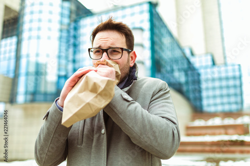 Businessman holding paper bag over mouth as if having a panic attack